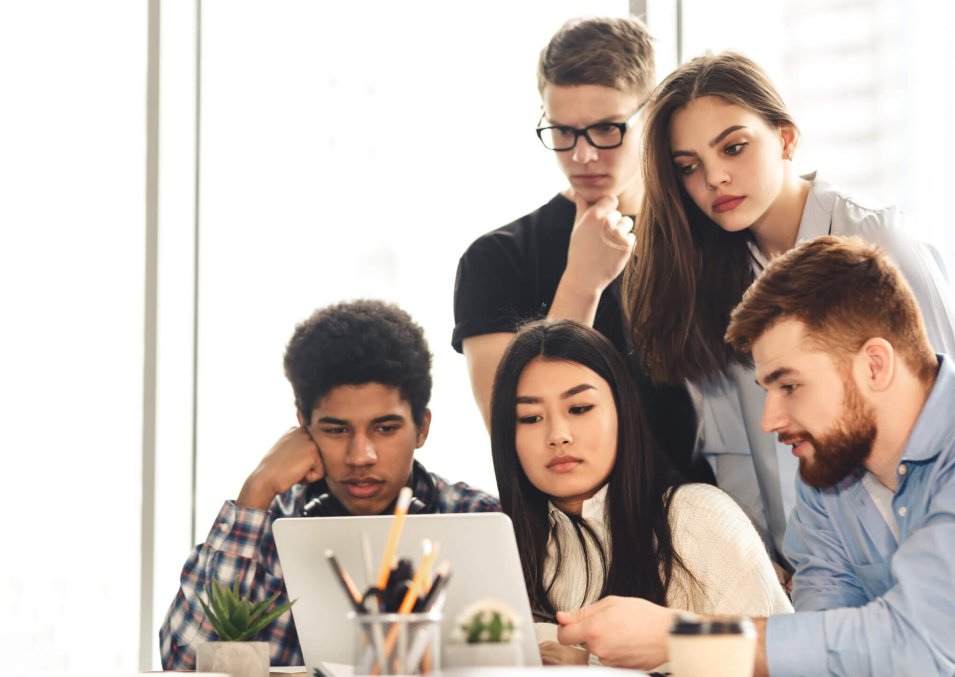 Remote education. A collaborative scene unfolds in the library where multiracial students use various devices to study. The environment is calm, with a focus on shared knowledge and technology.